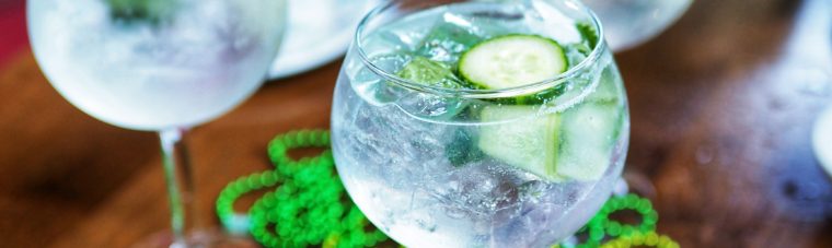 Dingle Irish Gin, Fever Tree Elderflower Tonic, Fresh Lime, Cucumber, Mint in a large wine goblet with cucumber and mint on a table with Irish beads and a Raglan Road Irish Hat